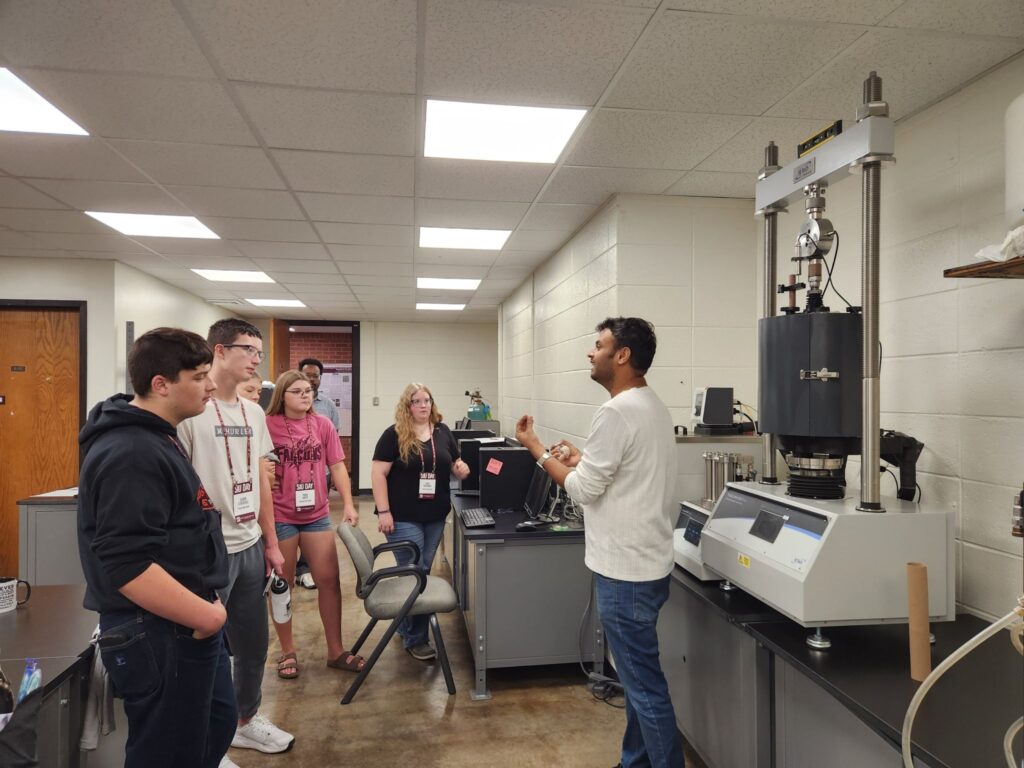 Visiting students learn about a geotechnical load frame during a GeoCARE Lab tour